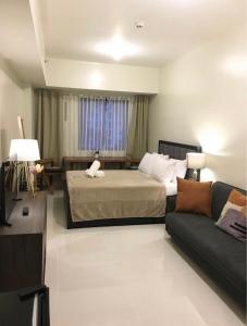 - une chambre avec un lit et un canapé dans l'établissement PREMIUM CONDO AT BRENTHILL BAGUIO, à Baguio