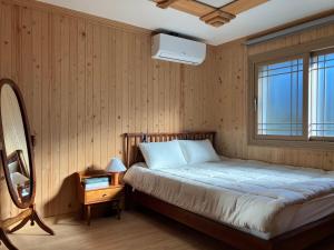 1 dormitorio con cama y ventana en Bijarim Healing Pension en Jeju