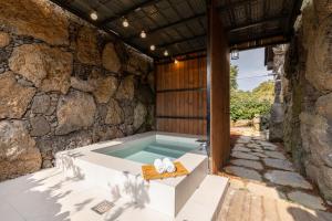 a bath tub in a stone building with two towels at Bijarim Healing Pension in Jeju