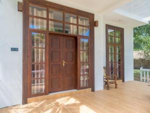 ein leeres Zimmer mit einer großen Holztür und Fenstern in der Unterkunft Dinuri villa in Tangalle