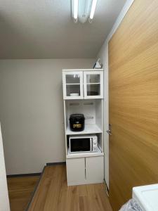 a kitchen with a microwave on a shelf next to a door at ACT Residence No.1 in Tokyo