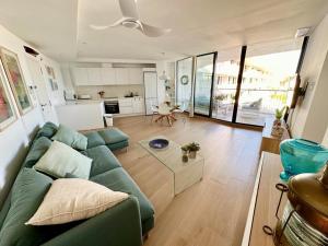 a living room with a green couch and a kitchen at Denia Beach 40 in Denia