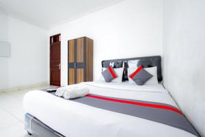 een slaapkamer met een groot wit bed met rode en blauwe kussens bij J&B Rooms Tomang Jakarta Mitra RedDoorz in Jakarta