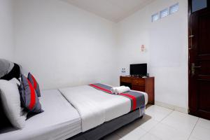 Un dormitorio con una cama y un televisor. en J&B Rooms Tomang Jakarta Mitra RedDoorz, en Yakarta