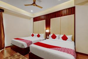 two beds in a hotel room with red pillows at OYO SAI GRAND LUXURY ROOMS in Tirupati