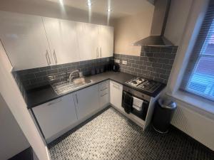 a small kitchen with white cabinets and a stove at Church View Apartment in Great Yarmouth