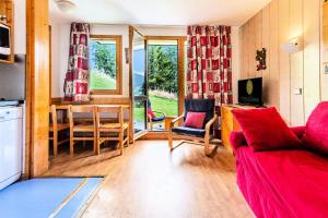 a living room with a red couch and a table at Résidence Les Brigues - maeva Home - Appartement 2 Pièces 6 Personnes - Co 014 in Courchevel
