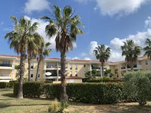 un bâtiment avec des palmiers en face de celui-ci dans l'établissement Appartement, 1 chambre, Piscine, Wifi..., à La Seyne-sur-Mer