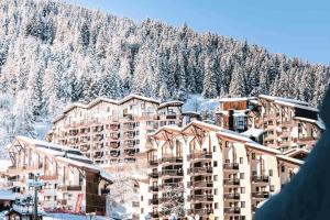 a person looking up at a hotel in the snow at Residence Le Grand Bois - maeva Home - Appartement 2 pièces 4 personnes - Sélection MAE-5824 in La Tania