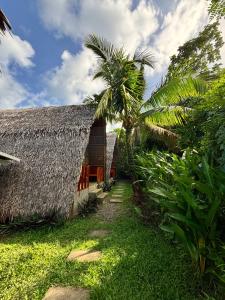 a building with a thatched roof and a palm tree at Triangle Palms Siargao in General Luna
