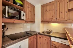 a kitchen with wooden cabinets and a sink and a microwave at Quartier La Forêt - maeva Home - Appartement 3 pièces 7 personnes - Sélec 124 in Valmorel