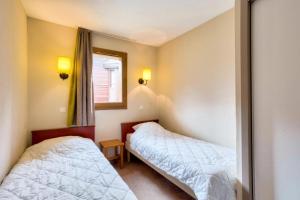 two beds in a room with a window at Quartier La Forêt - maeva Home - Appartement 3 pièces 7 personnes - Sélection MAE-7124 in Valmorel