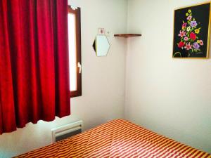 ein Schlafzimmer mit einem Bett und einem roten Vorhang in der Unterkunft Résidence Pic Du Midi - 2 Pièces pour 4 Personnes 624 in La Mongie