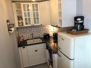 a small kitchen with white cabinets and a white refrigerator at BeachBude Apartments in Timmendorfer Strand