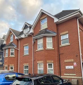 een rood bakstenen huis met auto's ervoor geparkeerd bij Mada Apartment Bournemouth 12 min walking to the beach in Bournemouth