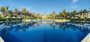 una piscina en un complejo con palmeras y sombrillas en Mysterio Pool Villas - Wyndham Garden Resort en Cam Ranh