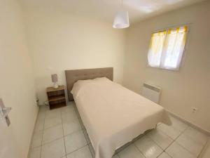 een witte slaapkamer met een bed en een raam bij Vue mer au coeur de Saint Mandrier, 3 chambres, climatisation, wifi (fibre) in Saint-Mandrier-sur-Mer