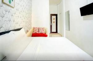 een witte kamer met een bed en een rode stoel bij RedDoorz near Plaza Araya Malang in Blimbing