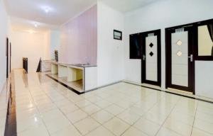 a large white room with a table and two doors at RedDoorz near Plaza Araya Malang in Blimbing