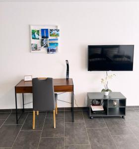 a desk with a chair and a television on a wall at MY HOME N 35 in Villingen-Schwenningen