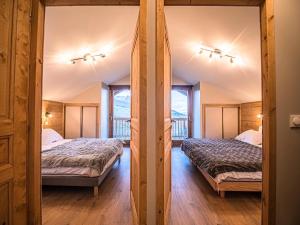 two beds in a room with two windows at CHALET LUMI - Chalet CHALET MEIJE pour 6 Personnes 094 in Valmorel