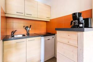 una pequeña cocina con armarios de madera y fregadero en Résidence Plagne Lauze - maeva Home - Appartement 3 pièces 7 personnes - S 954 en Mâcot La Plagne