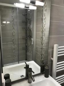 ein Bad mit einem Waschbecken und einer Dusche mit einem Spiegel in der Unterkunft Résidence Gentiannes - Appartements pour 5 Personnes 544 in Vars