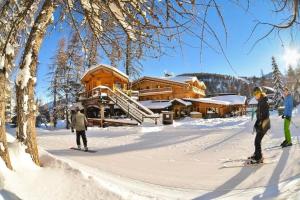 tres personas esquiando en la nieve frente a una cabaña en Résidence Centre Vars - Studio pour 3 Personnes 914, en Vars