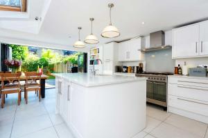 a kitchen with white cabinets and a dining table at Veeve - By Richmond Lock in Isleworth