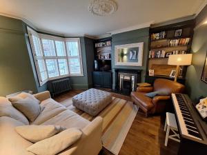 a living room with a couch and a piano at Veeve - By Richmond Lock in Isleworth
