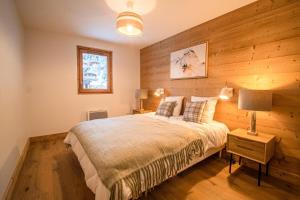 a bedroom with a bed with a wooden wall at Résidence LUMI BATIMENT B - Appartement LUMI B pour 7 Personnes 224 in Valmorel