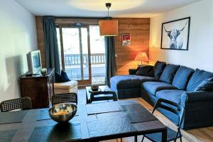 uma sala de estar com um sofá azul e uma mesa em Résidence LUMI BATIMENT B - Appartement LUMI B pour 5 Personnes 024 em Valmorel