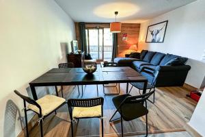 un soggiorno con tavolo, sedie e divano di Résidence LUMI BATIMENT B - Appartement LUMI B pour 5 Personnes 024 a Valmorel