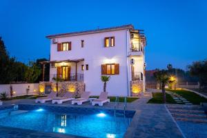 a villa with a swimming pool at night at Kostis Orange Resort in Volos