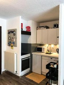 a small kitchen with a stove and a microwave at Résidence Cote Brune 2 - Studio pour 4 Personnes 394 in Vénosc