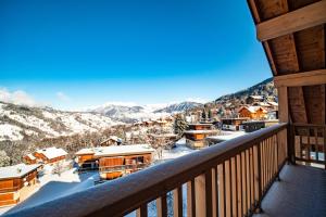 a balcony with a view of a town in the snow at Résidence LUMI BATIMENT B - Appartement LUMI B ALPAGA pour 8 Personnes 044 in Valmorel