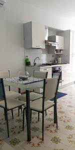 Yellow e Blu appartaments في جوليانوفا: مطبخ مع طاولة زجاجية وكراسي في مطبخ