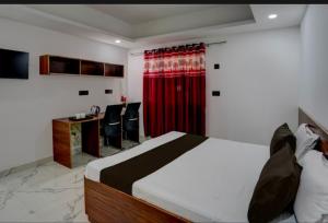 um quarto com uma cama, uma secretária e uma cortina vermelha em The Simran suites em Greater Noida