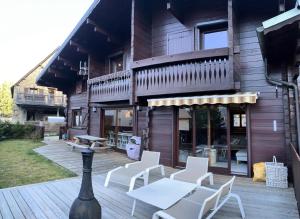 a wooden deck with white chairs and a building at Chalet Gaspard - Chalets pour 16 Personnes 494 in Vénosc