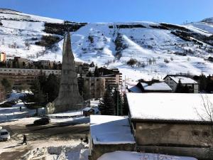 een met sneeuw bedekte stad met een kerk en een berg bij Résidence Grande Chaume - 2 Pièces pour 4 Personnes 344 in Vénosc