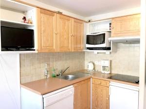 een keuken met houten kasten, een wastafel en een magnetron bij Résidence Grande Chaume - 2 Pièces pour 4 Personnes 344 in Vénosc