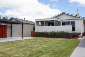 une maison blanche avec une pelouse devant elle dans l'établissement Central Villa Oasis, à Whangarei