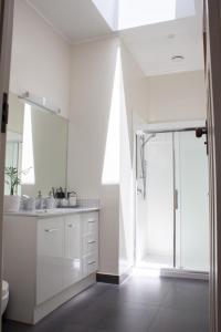 a white bathroom with a shower and a sink at Central Villa Oasis in Whangarei