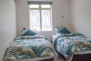 a bedroom with two beds and a window at Central Villa Oasis in Whangarei