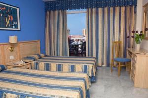 a hotel room with two beds and a window at Marola Park in Playa de las Americas