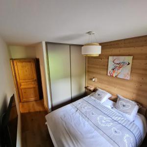 a bedroom with a white bed with a wooden wall at Résidence LUMI BATIMENT B - Appartement LUMI B 834 in Valmorel