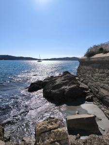 eine felsige Küste mit einem Boot im Wasser in der Unterkunft Les Résidences du Mourillon in Toulon