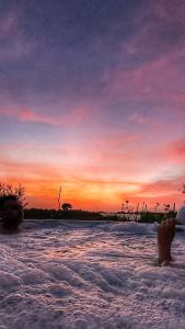 een persoon staat in het water bij zonsondergang bij Ciriga Sicily Glamping Resort in Santa Maria Del Focallo