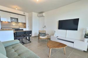 ein Wohnzimmer mit einem Sofa und einem Flachbild-TV in der Unterkunft Splendide T2 Vue mer Valras-Plage ! in Valras-Plage