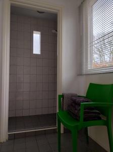 een groene stoel in een badkamer met een douche bij Drenths Landgoed, Lekker uit in Annerveenschekanaal